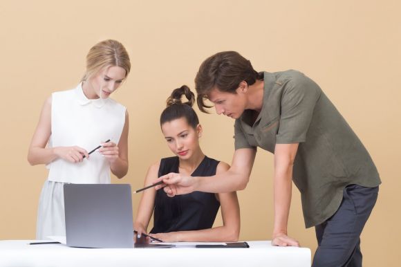 Buisness Process - man teaching woman while pointing on gray laptop